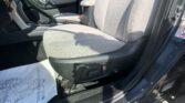 Driver-side interior of a car with gray fabric seats, center console, handbrake, and keys hanging near the door.