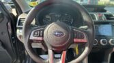 Interior view from the driver’s seat showing the steering wheel, instrument cluster, and a touchscreen infotainment system in a car parked outdoors in a lot.