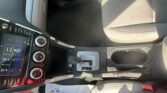 Interior of a car focusing on the center console: touchscreen, climate controls, gear selector, and front passenger seat with patterned fabric.