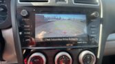 Car infotainment screen showing rearview camera with parking guidelines and text 'Check Surroundings Before Backing Up' for backing up safety.