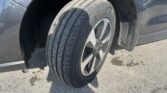 Close-up of a car tire and alloy wheel in a wheel well of a dark blue vehicle.