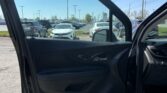 View from an open car door into a crowded parking lot of cars under a clear blue sky, with a Toyota sign visible in the distance.