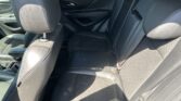 Rear interior of a car showing black leather back seats and headrests with door panel in view.