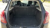 Open SUV trunk with spacious cargo area and back seats visible, dealership lot in background, light coming in from outside through rear window.