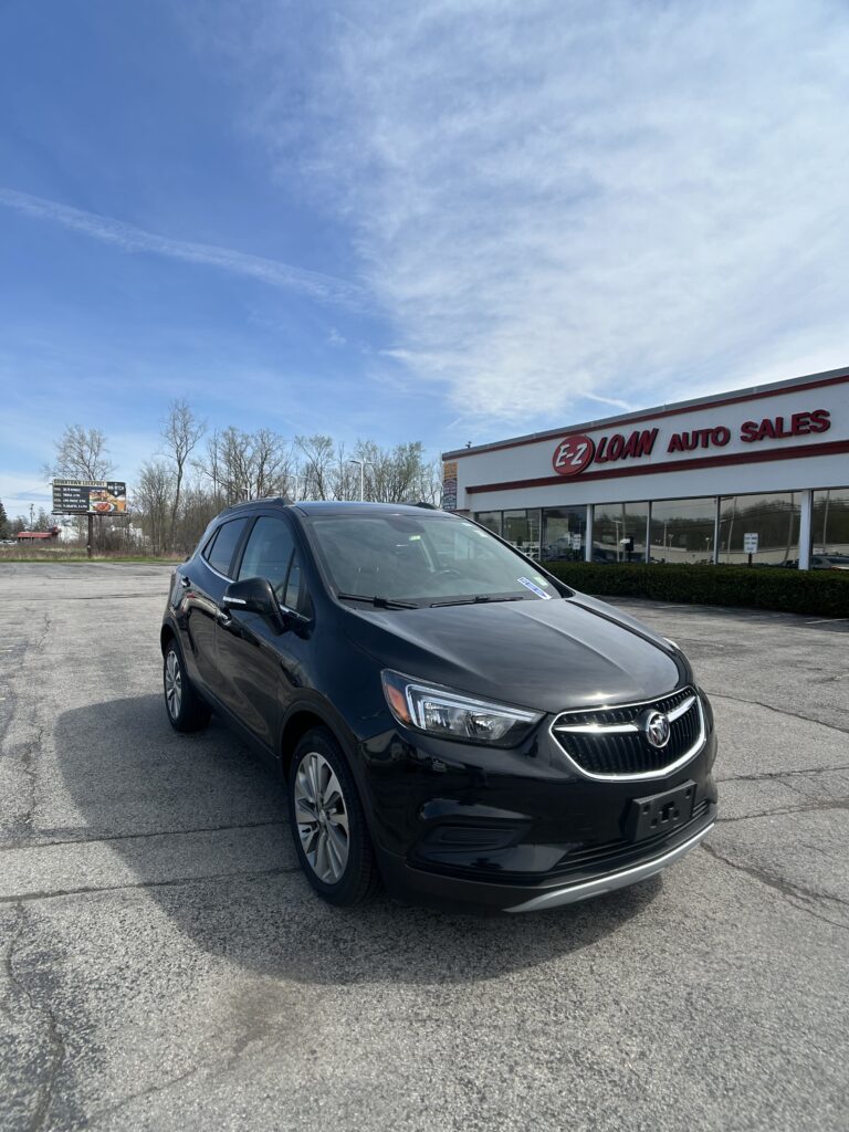 Black Buick SUV parked in front of EZ Loan Auto Sales building on a clear day with blue sky.