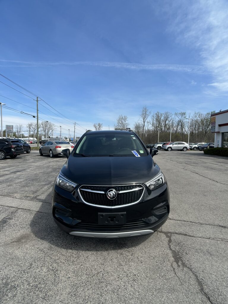 Front view of a black Buick SUV parked in a car lot on a sunny day with a blue sky above.