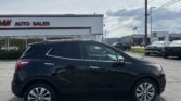 Black SUV parked in a car dealership lot with a white building that reads 'AUTO SALES' in the background, power lines overhead.
