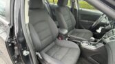 Interior of a car showing the front driver and passenger seats, steering wheel, and center console visible from the open door.