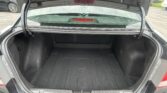 Open car trunk with empty cargo area, view of rear window and parking lot beyond the car's tailgate