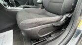 Close-up of a car's front interior: black fabric seats, center console with gear shifter and cup holder, and a passenger door panel visible on the left side.