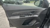 Interior of a car door panel with power window controls, view of a dealership parking lot outside the window