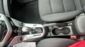 Interior of a car focusing on the center console: gear shifter, cup holders, and front seats in black fabric.