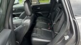 Interior of a black leather SUV with the rear seats and front seat visible, viewed from the open rear door, showing seatbelts.