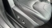 Black leather car seat with perforated center panel and visible side adjustment lever inside a Jeep.