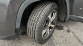 Close-up of front left wheel and fender of a gray pickup/SUV with mud around the wheel well and tread visible in the tire surface