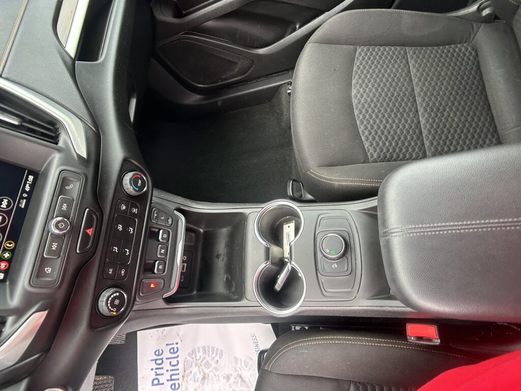 Interior of a car showing the center console with cup holders, gear selector, climate controls, and passenger seat seen from above.