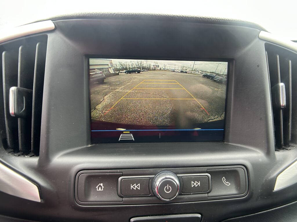 Rear backup camera view on the in-dash screen with parking-guidance lines behind the car in a parking lot