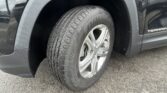 Close-up of a vehicle tire and wheel, with the fender and 'Terrain' badge visible on the side of a dark SUV partner vehicle.