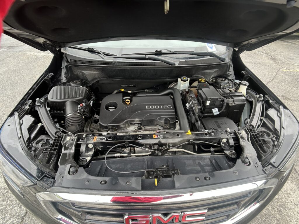 Open car hood showing engine bay with ECOTEC cover, battery, and various hoses and components.