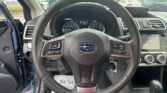 Driver's perspective of a car interior showing a textured steering wheel, instrument cluster, and center console with infotainment screen and climate controls