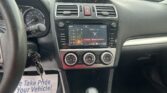 Driver’s view of the car interior: steering wheel, speedometer, and center touchscreen displaying FM radio and climate controls.