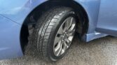Close-up of a blue car's tire and alloy wheel inside the wheel arch.