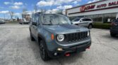 Front corner of a gray Jeep in a parking lot outside an auto dealership with an EZ Loan Auto Sales sign on the building behind.