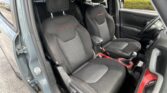 Front interior of a dark SUV showing two black fabric seats with red contrast stitching and 'Trailhawk' embroidery on the headrests/seat backs. The steering wheel is on the right side.