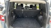 Open hatch reveals SUV cargo area with third-row seats up, black carpet, and side pockets.
