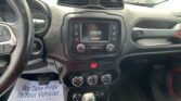 Jeep dashboard interior with central touchscreen showing 'Jeep', air vents, and climate controls; a flyer on the floor reads 'We Take Pride In Your Vehicle!'