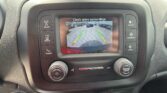 In-dash touchscreen showing a backup camera view with parking guide lines in a parking lot.
