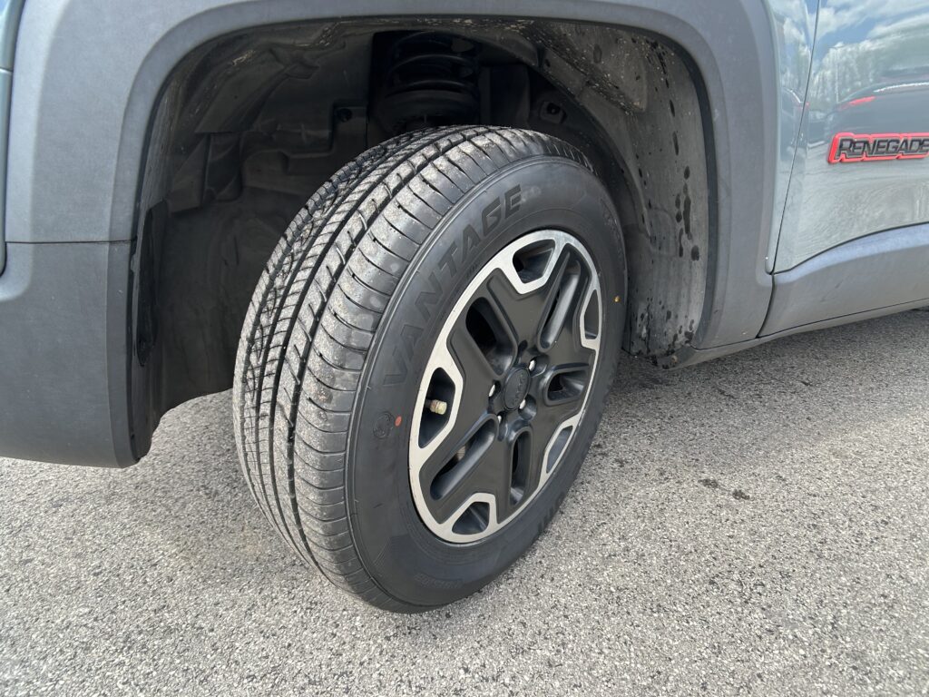 Close-up of a gray SUV wheel and tire in the wheel well, with mud on the fender and inner lining visible.