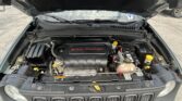 Open car hood view of a 2.4L multiair engine bay with battery, coolant reservoir, and air intake; front grille and wipers visible in the background.