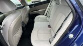 Rear interior of a blue sedan with beige fabric seats, a three-seat bench and headrests visible.