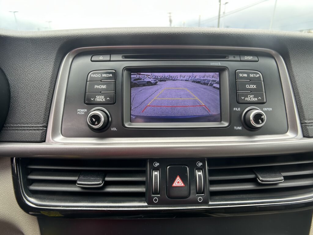 Car infotainment screen showing a rearview camera feed with parking guidelines in a dealership-like setting.