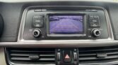 Car infotainment screen showing a rearview camera feed with parking guidelines in a dealership-like setting.