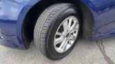 Close-up of a blue car's front wheel: tire with alloy rim and visible Kia logo inside the wheel well.