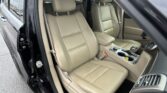 Beige leather front seats and center console visible in an SUV with the driver’s door open.
