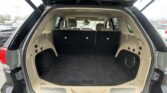 Open SUV hatch revealing a spacious beige cargo area with third-row seats upright and black carpeting inside, exterior dark paint visible.