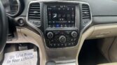 Interior of a car showing the center touchscreen climate controls, gear shifter, and cup holder, with a flyer on the passenger floor reading, “We Take Pride In Your Vehicle.”