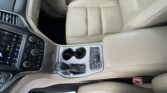Beige leather car interior with a center console, cup holders, gear shifter, and touchscreen dashboard visible.