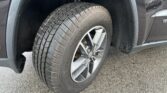Close-up of a tire mounted on a dark SUV wheel, inside the front wheel well.
