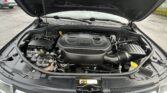 Under-hood view of a vehicle with the hood raised, showing a V6 engine cover and surrounding engine components