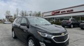 Black Chevrolet SUV in the foreground of a car lot, with an EZ LOAN AUTO SALES storefront in the background and cloudy sky above.