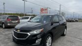 Black Chevrolet SUV in the foreground at EZ Loan Auto Sales lot with a sign and other cars behind.