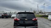 Rear view of a black Chevrolet Equinox SUV in a parking lot with power lines overhead.