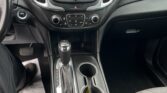 Interior of a car with a center console: touchscreen display, climate controls, gear shifter, and cup holders.