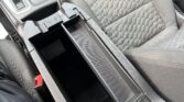 Center console with two cup holders, open storage compartment, and front seats in a car interior.