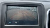 Car's infotainment screen displaying a rearview camera with parking guide lines in an outdoor lot