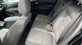 Rear passenger area of a black sedan with gray fabric seats and seat belts visible, door panel and window frame in view